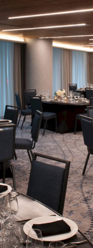 The image shows a decorated banquet hall with round tables set with plates, glasses, and napkins, featuring elegant candles and flower arrangements.