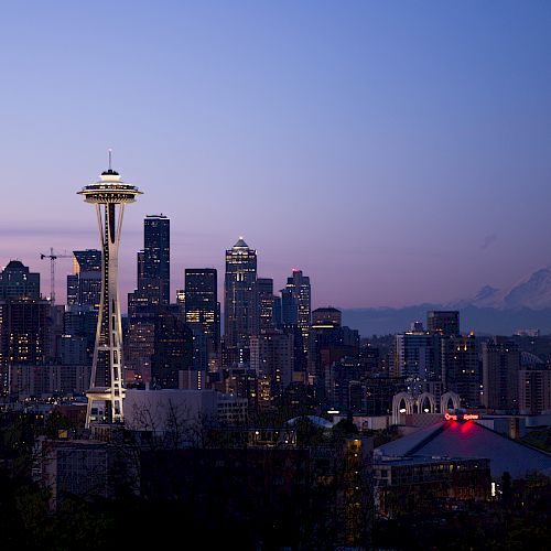 This image showcases the Seattle skyline at dusk, featuring the iconic Space Needle, with Mount Rainier visible in the background.