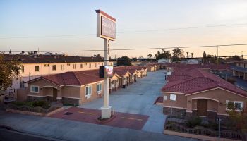 The image shows a residential area with multiple single-story houses featuring red-tiled roofs and a central sign for a motel or inn.